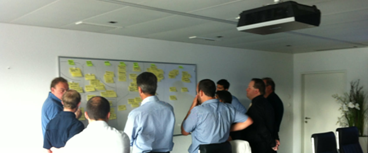 Équipe réunie devant un tableau de post-it